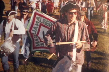 Founder-Steve-Hager-leads-the-Freedom-Fighter-parade-at-the-Midwest-Harvest-Festival-in-Madison-Wisconsin-1989.-That-is-the-Michigan-focalizer-of-the-group-Thom-Harris-on-drums-right-behind-him